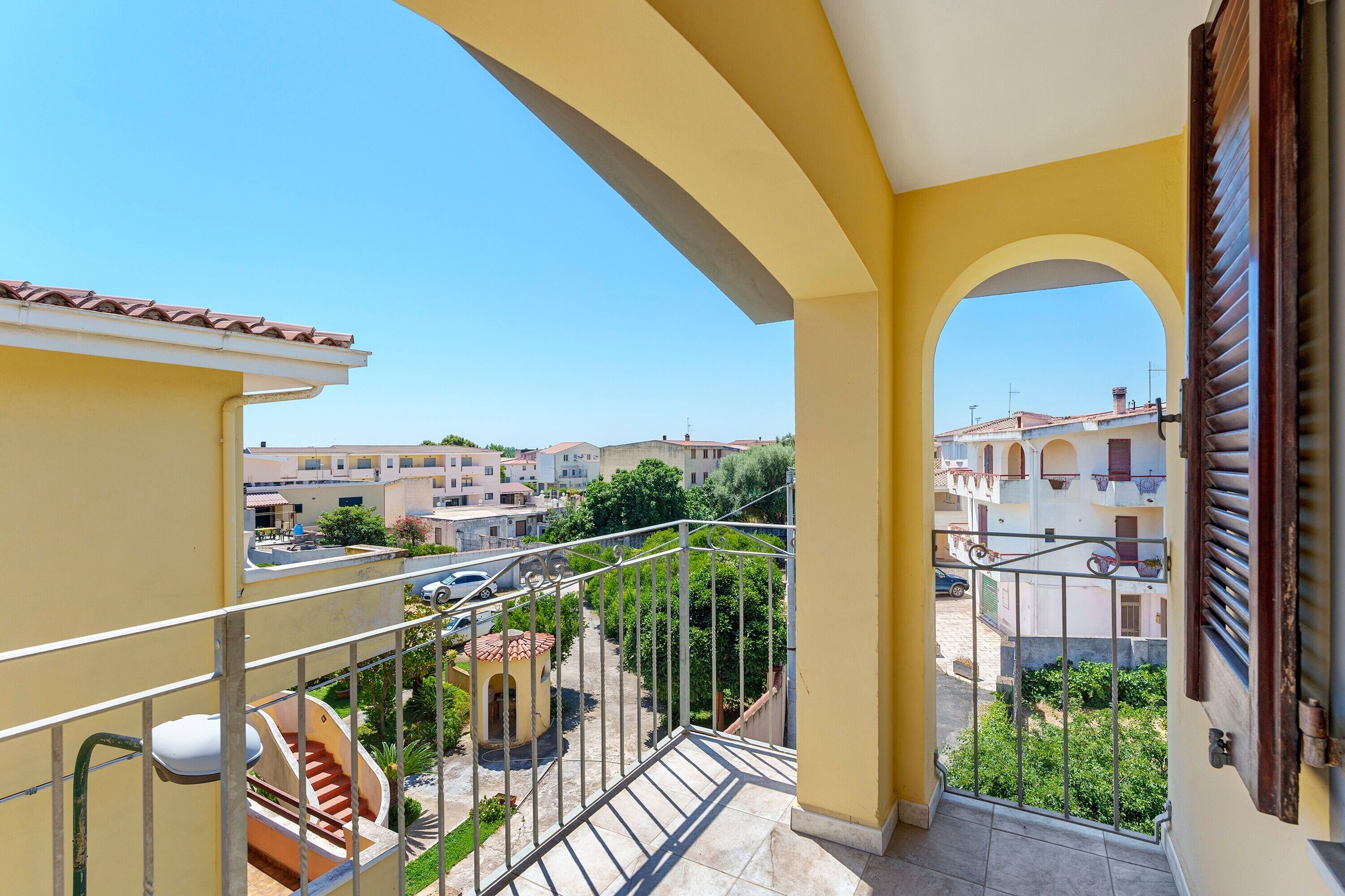 Un balcon donnant sur un quartier résidentiel, avec un escalier et une balustrade.