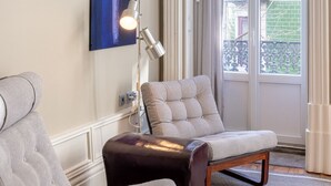 Une pièce avec une grande fenêtre, une chaise, un canapé et une lampe.