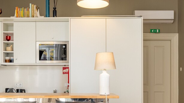 Une chambre d’hôtel avec un lit, un bureau avec une lampe, un minibar et une vue sur le couloir.