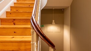 Un escalier en bois, avec des balustrades blanches et une main courante sombre, menant à un palier.