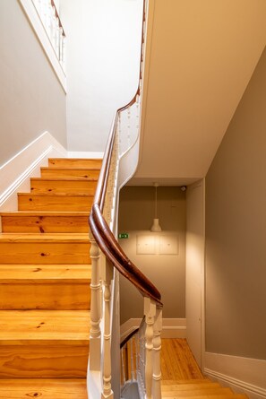 A wooden staircase with white balusters and a dark handrail leading to a landing. - Casa do Ofício - Bookseller 2 by Hosty (Porto)