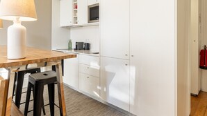 Une cuisine moderne avec des meubles blancs, une table en bois et un luminaire suspendu.