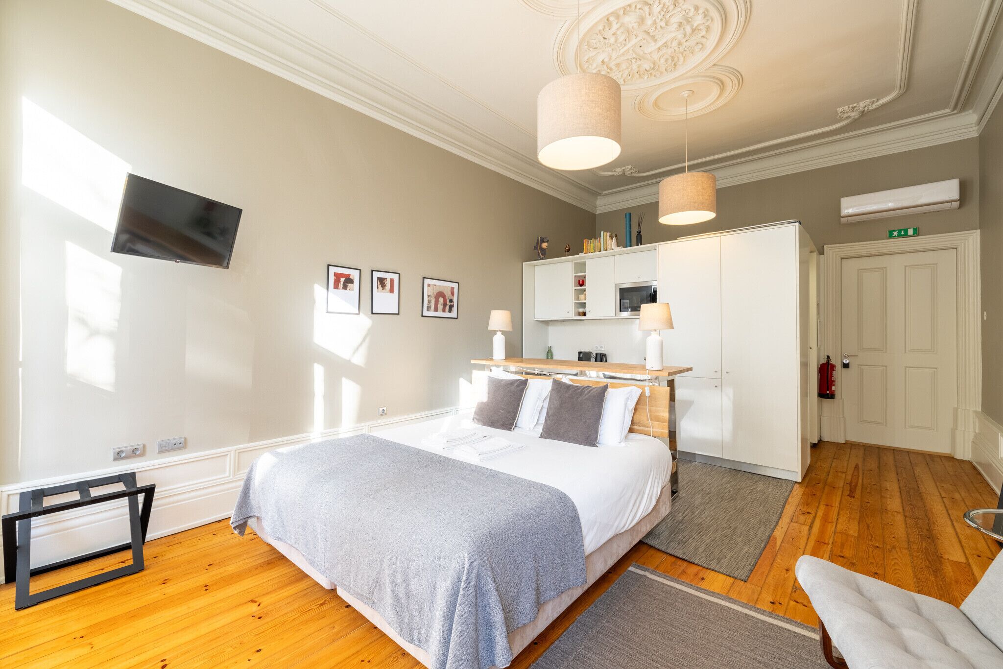 Een moderne hotelkamer met een bed, een televisie, een bureau en een kledingkast.