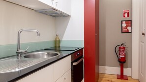A kitchen with a sink, cabinets, and a fire extinguisher. - Casa do Ofício - Bookseller 4 by Hosty (Porto)