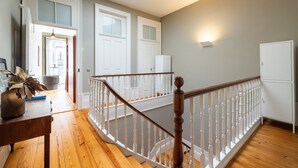 A staircase with white balusters and a wooden handrail, leading to an upper floor. - Casa do Ofício - Bookseller 4 by Hosty (Porto)