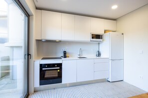 A modern kitchen with white cabinets, a microwave, a refrigerator, and an oven. - Casa do Ofício - Galerista by Hosty (Porto)