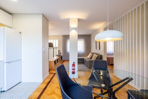 A modern living room with a glass table, black chairs, a sofa, and a hanging light fixture. - Casa do Ofício - Galerista by Hosty (Porto)