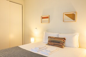 A hotel room with a bed, pillows, a bedside lamp, and a wall-mounted artwork. - Casa do Ofício - Galerista by Hosty (Porto)