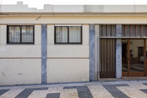 A building facade with a tiled entrance, two windows with blinds, and a door with a metal gate. - Casa do Ofício - Hosty's Gallery Owner (Porto)