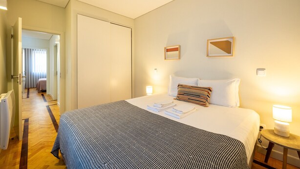 A hotel room with a bed, bedside lamps, a door, and a hallway. - Casa do Ofício - Galerista by Hosty (Porto)