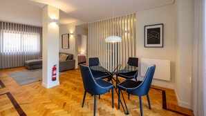 A modern living room with a sofa, a dining table with chairs, a fire extinguisher, and a radiator. - Casa do Ofício - Galerista by Hosty (Porto)