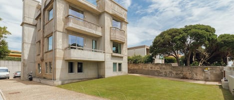 A modern multi-story building with a stone facade, a paved driveway, and a well-maintained lawn.