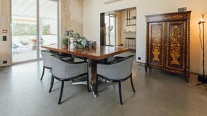 Un comedor con una mesa de madera, cuatro sillas, un aparador con detalles ornamentales y vistas a través de un ventanal.