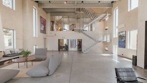 Un amplio vestíbulo con escaleras, zonas de estar y grandes ventanales.