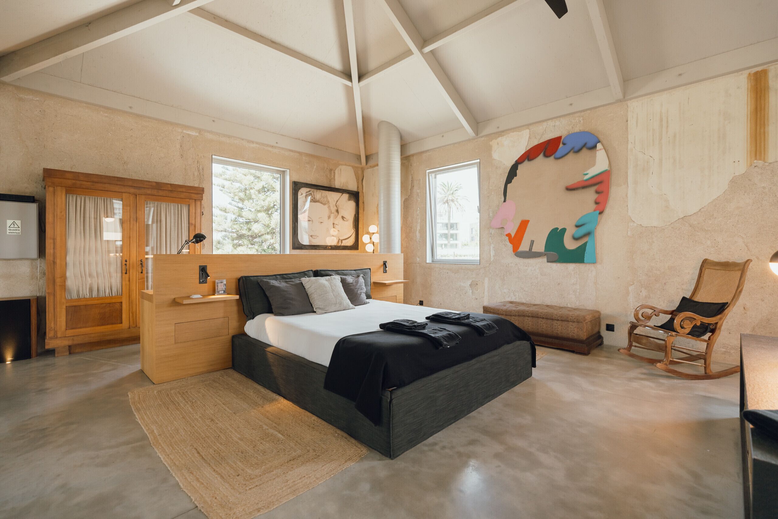 Une chambre à coucher avec un lit, une chaise, un bureau et une grande fenêtre.