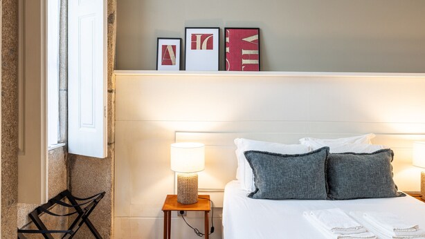 Et hotelværelse med en seng, to sengeborde, lamper og et vindue med gardiner.