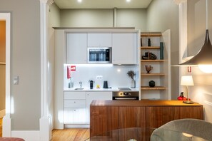 A modern kitchen with white cabinetry, a built-in microwave, a coffee maker, and a wooden countertop. - Casa do Ofício - Bookseller 1 by Hosty (Porto)