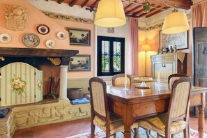 Zona pranzo con tavolo in legno, sedie e camino.