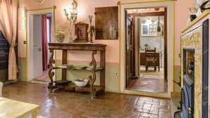 A traditional interior with a wooden table, a chandelier, and a doorway leading to a kitchen area. - Historic Villa with Florence View and Hot Tub (Lastra a Signa)