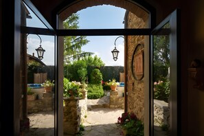 Un arco d'ingresso conduce a un sentiero in pietra, circondato da piante in vaso e un giardino curato.