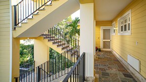 A yellow building with a staircase, a door, and a window with shutters. - Stylish 3BR Penthouse Ocean Views, Sosúa Center (Sosúa)