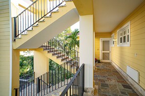 A yellow building with a staircase, a door, and a window with shutters. - Stylish 3BR Penthouse Ocean Views, Sosúa Center (Sosúa)