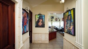 A hallway with a marble floor, wooden doors, and artwork on the walls. - Stylish 3BR Penthouse Ocean Views, Sosúa Center (Sosúa)