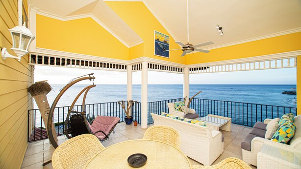 A balcony with wicker furniture, a ceiling fan, and a view of the ocean. - Stylish 3BR Penthouse Ocean Views, Sosúa Center (Sosúa)