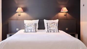 Een hotelkamer met een groot bed, twee bedlampjes en een donkere muur.
