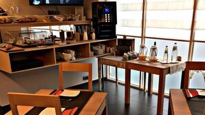 A modern dining area with wooden furniture, a television, and a kitchen area with a refrigerator and shelves. - Hôtel Le 24 (Spa)