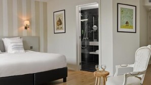 A hotel room with a bed, bedside lamps, a chair, and a small table. - Hôtel Le 24 (Spa)