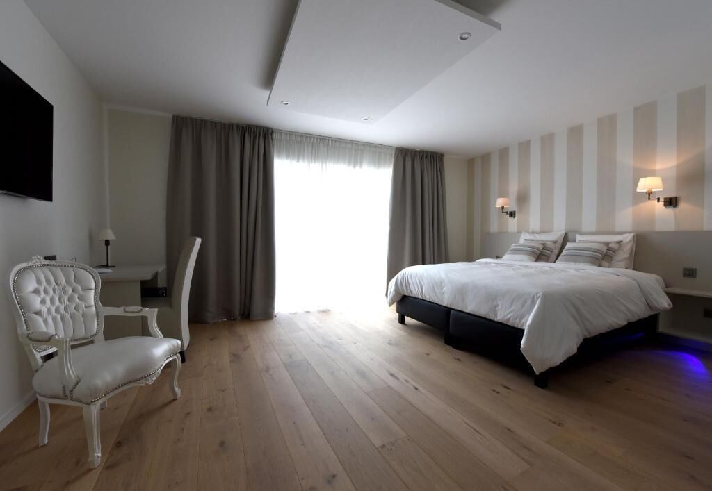 A hotel room with a bed, a chair, a desk, and a TV.