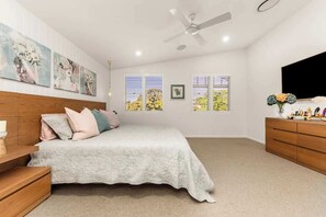 A bedroom with a bed, wooden headboard, bedside tables, a dresser, a ceiling fan, and artwork on the walls. - The Gables - Pool - Fire & Luxury (Tighes Hill)
