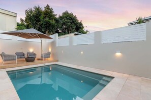 A swimming pool with a white fence, lounge chairs, and an umbrella. - The Gables - Pool - Fire & Luxury (Tighes Hill)
