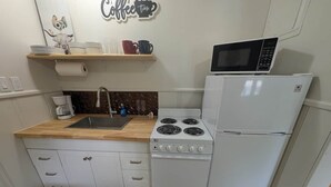Cozinha compacta com pia, fogão, micro-ondas e geladeira.
