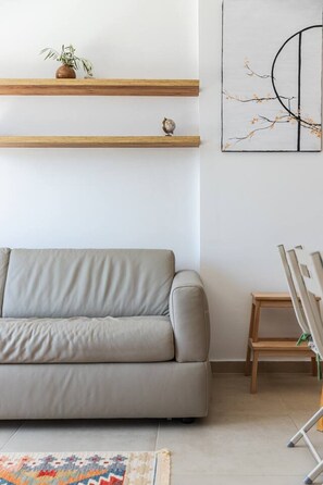 Una sala de estar con un sofá, una mesita y un cuadro en la pared.
