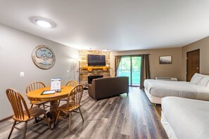 A modern room with a stone fireplace, a flat-screen TV, a dining table with chairs, and a sofa. - Cozy 1 bedroom located on Granite Peak, Unit 7 (Wausau)