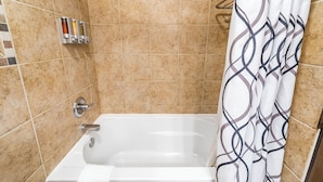 Un bagno con vasca, tenda da doccia e porta asciugamani con articoli da toilette.