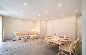 A modern living room with a sofa, dining table, and chairs, a lamp, and a door. - A PERFECT COMBINATION OF STYLE, COMFORT & AN UNBEATABLE LOCATION IN THE HEART (Cannes)
