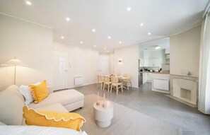 Ein modernes Wohnzimmer mit einer Couch, einem Esstisch mit Stühlen, einer Küchenzeile und einem Kamin.