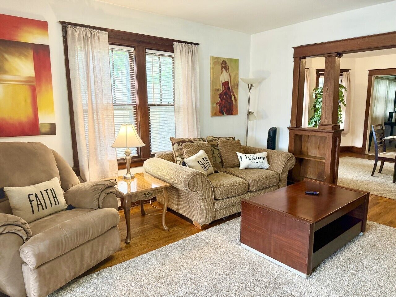 Una sala de estar con un sofá, un sillón, una mesa de centro, una lámpara y un cuadro en la pared.