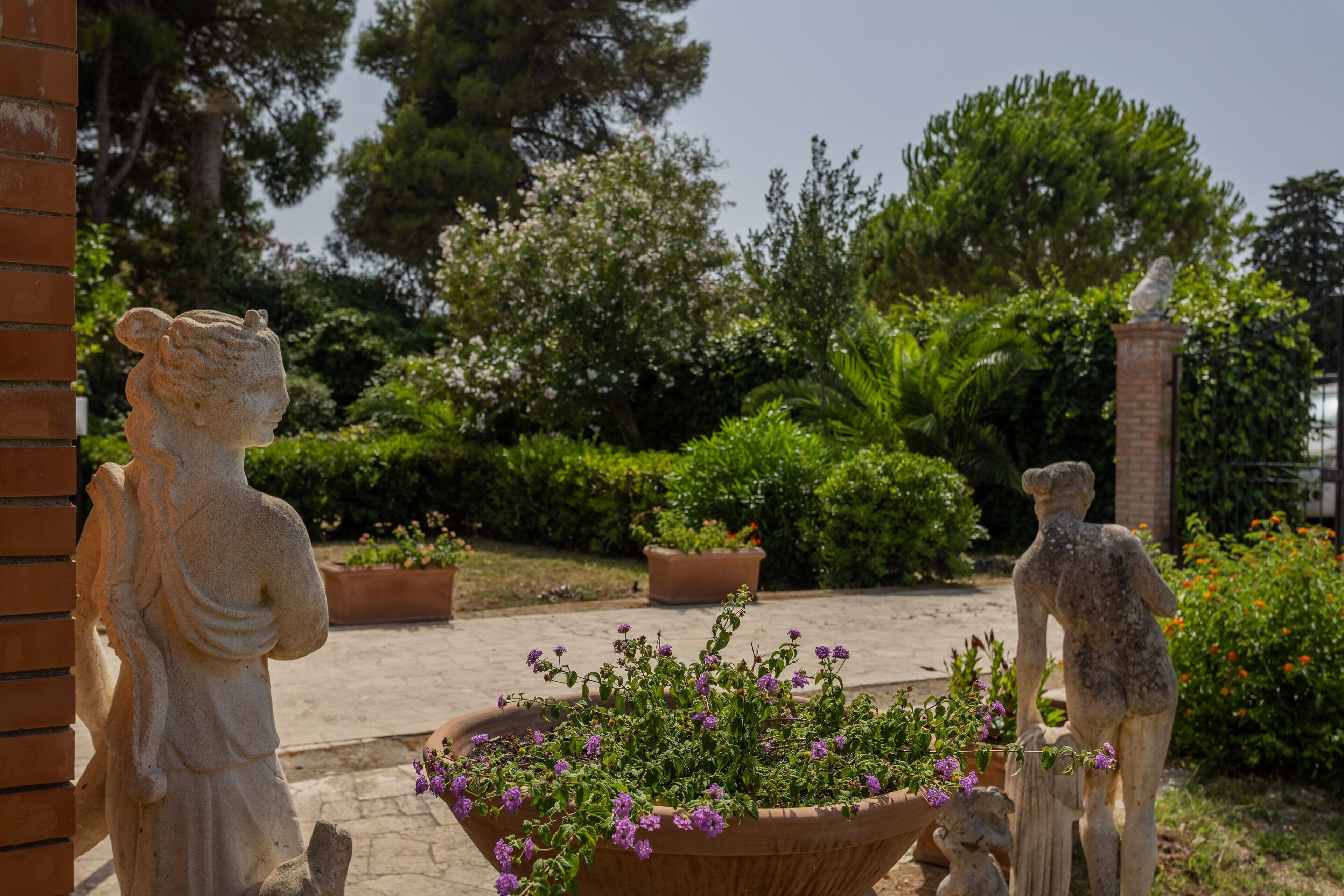 A garden with statues and potted plants.