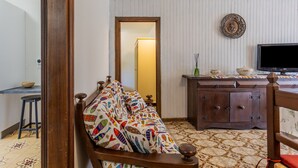Een kamer met een bed, een houten dressoir, een televisie en een klein tafeltje met een kom en een kaars.