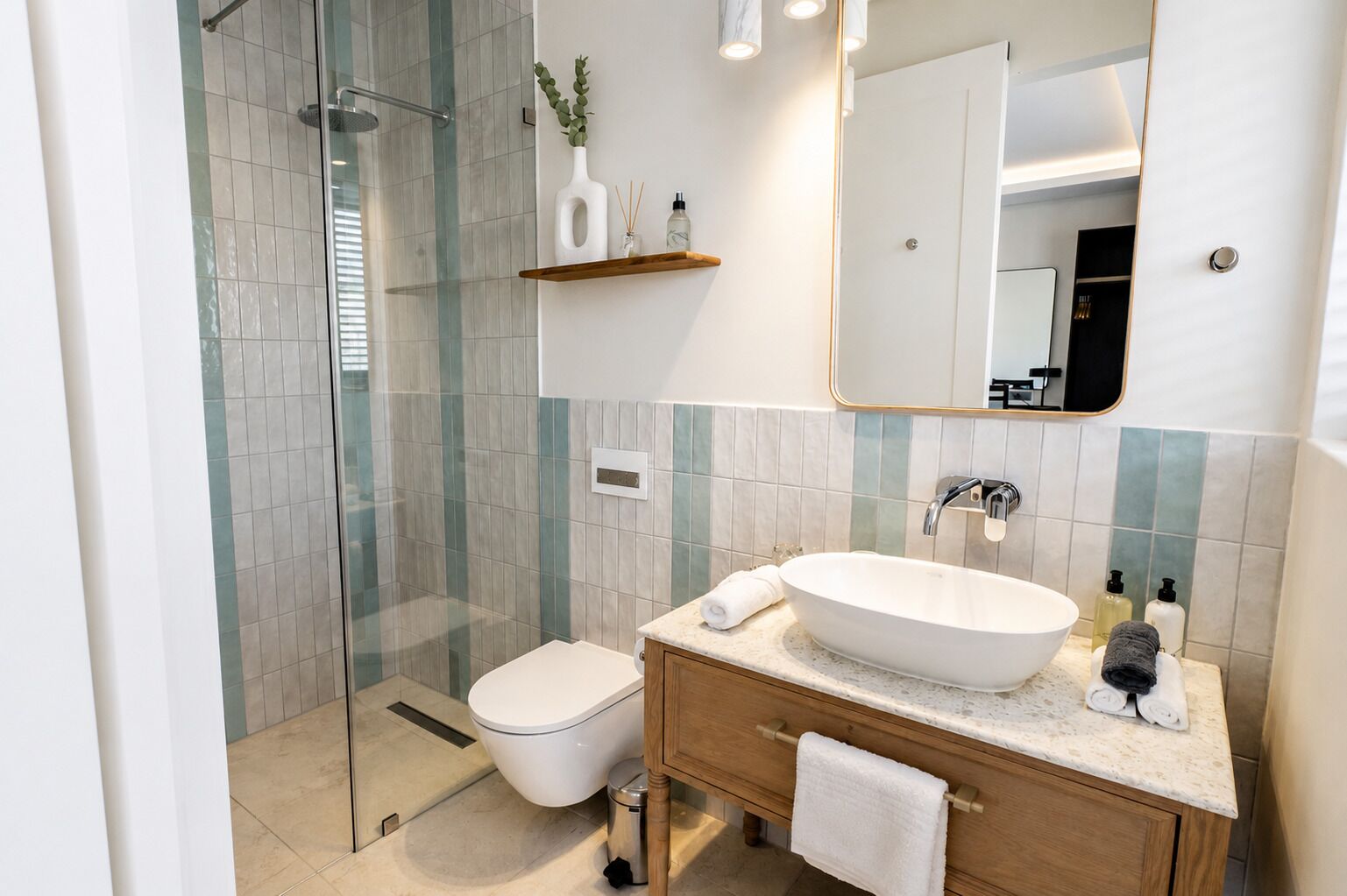 A modern bathroom with a glass shower enclosure, a white sink, and a wooden vanity.
