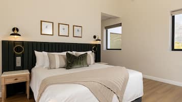 A bedroom with a bed, bedside tables, a nightstand, a window, and wall-mounted artwork.