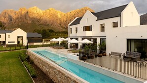 Een modern hotel met een zwembad, terras en uitzicht op de bergen.