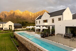 Un hotel moderno con piscina, mobiliario exterior y vistas a la montaña.