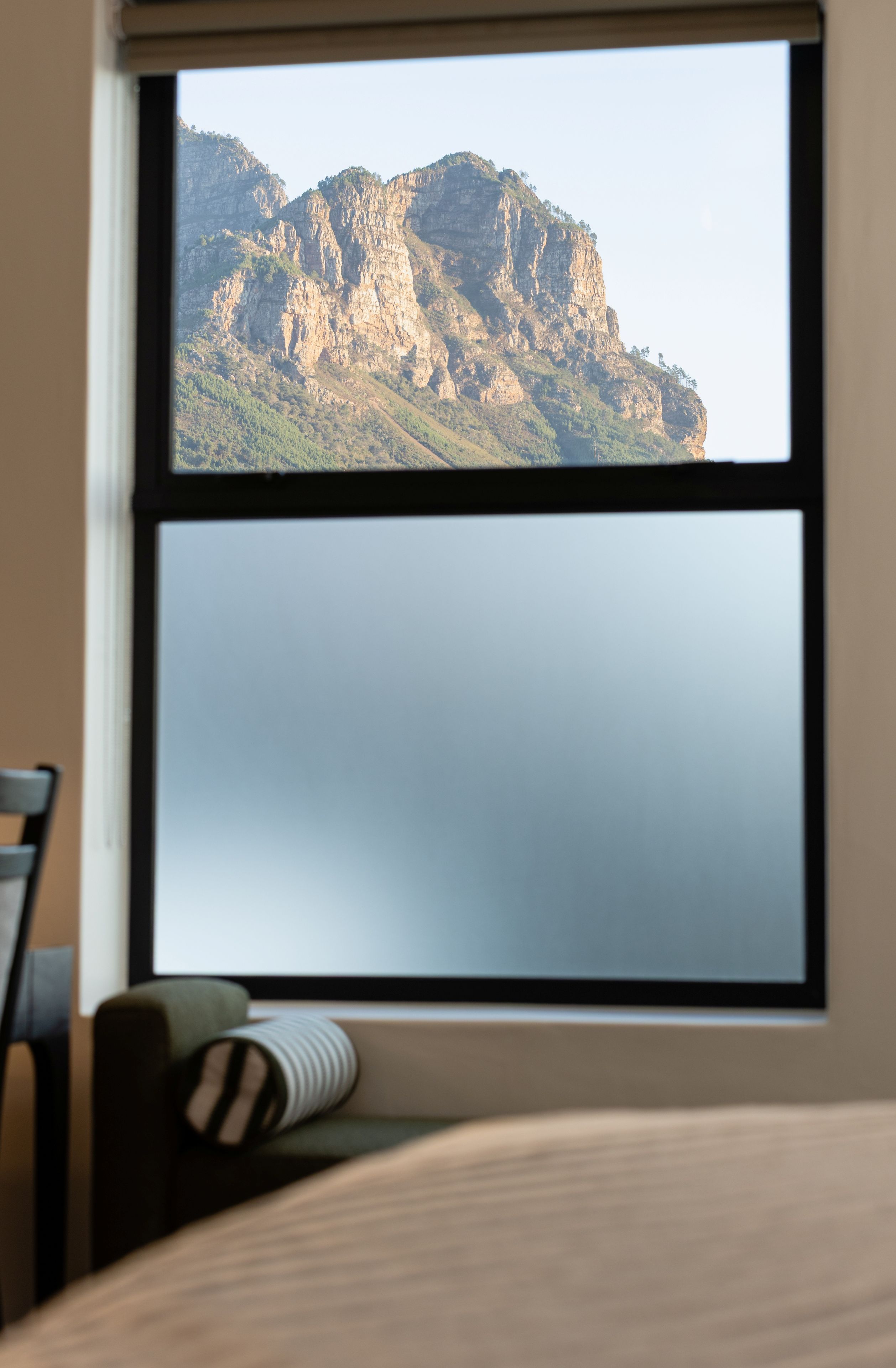 A room with a large window overlooking a mountainous landscape.