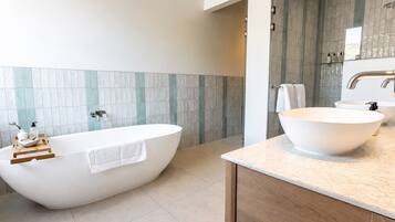Un baño moderno con una bañera independiente, un lavamanos grande y un mueble de tocador de madera.