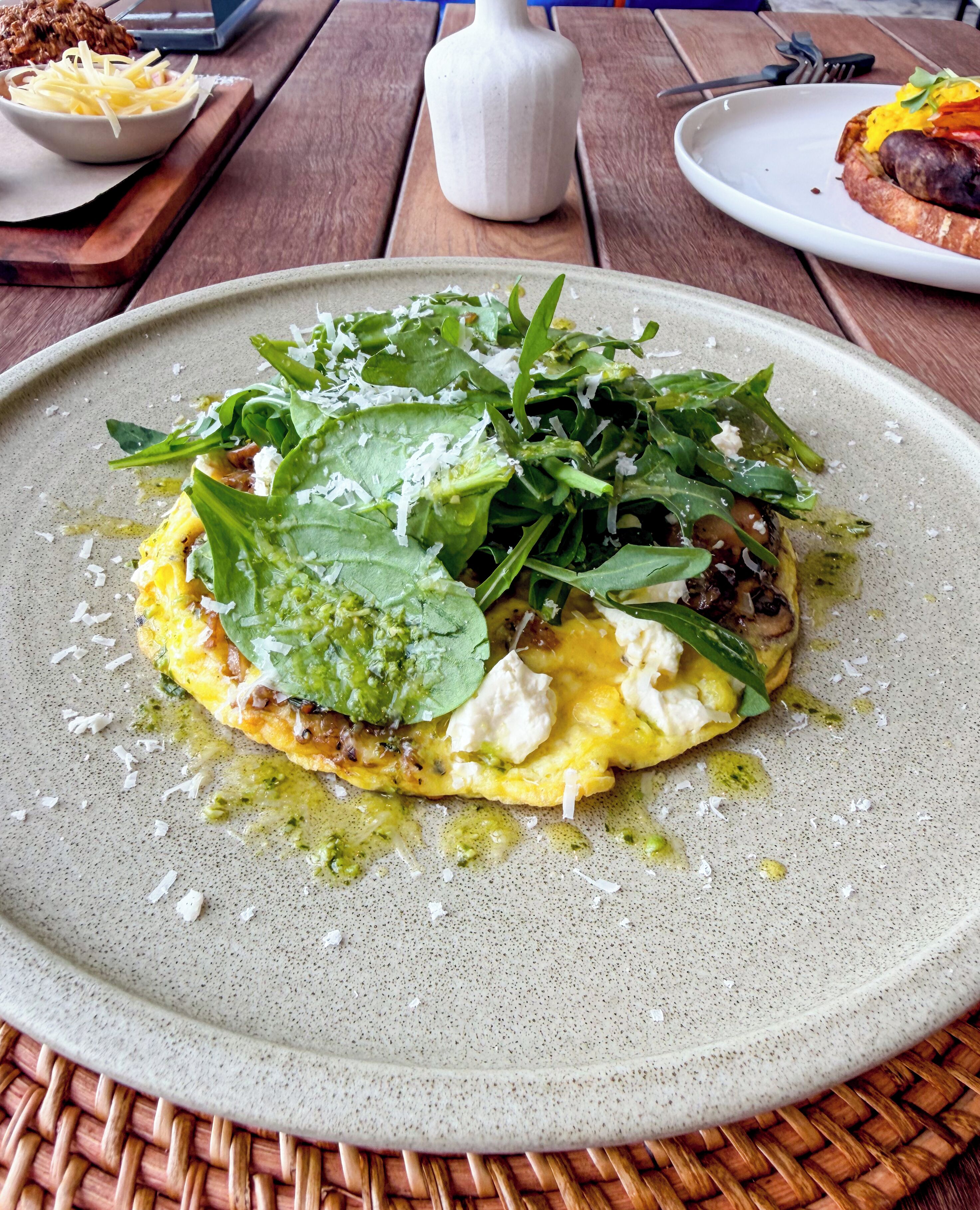 A plate of food with greens and cheese on a speckled ceramic plate.